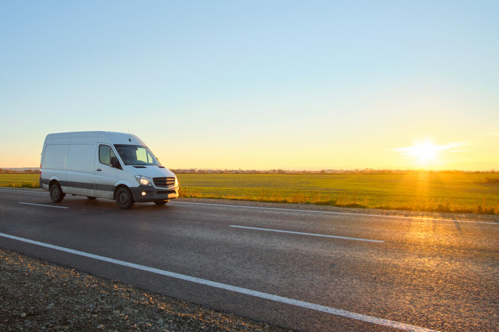 Small cargo van driving on highway hauling goods. Delivery transportation and logistics concept
